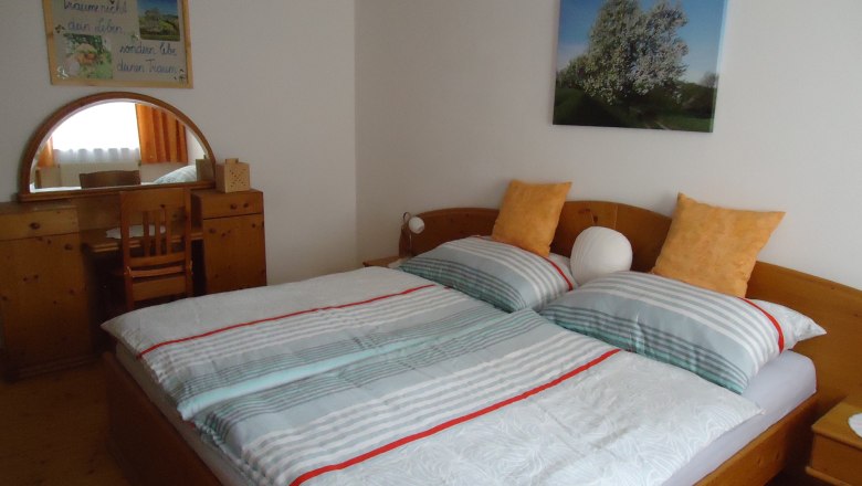 Gemütliches Schlafzimmer mit Doppelbett, Holzmöbeln und Wandbildern.