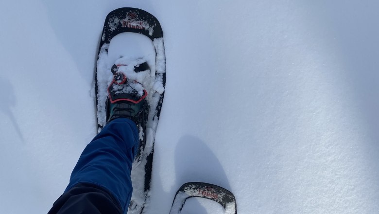 Person mit Schneeschuhen auf verschneitem Boden.