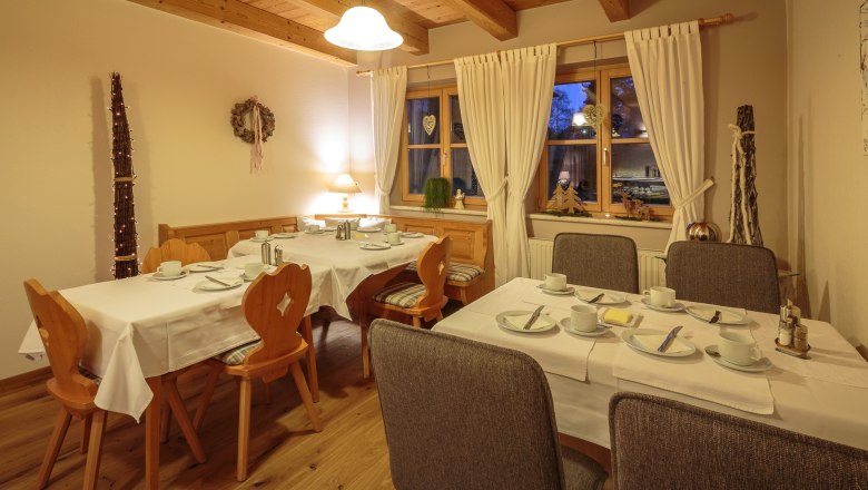 Gem&uuml;tlicher Fr&uuml;hst&uuml;cksraum mit gedeckten Tischen, Holzm&ouml;beln und Dekorationen.