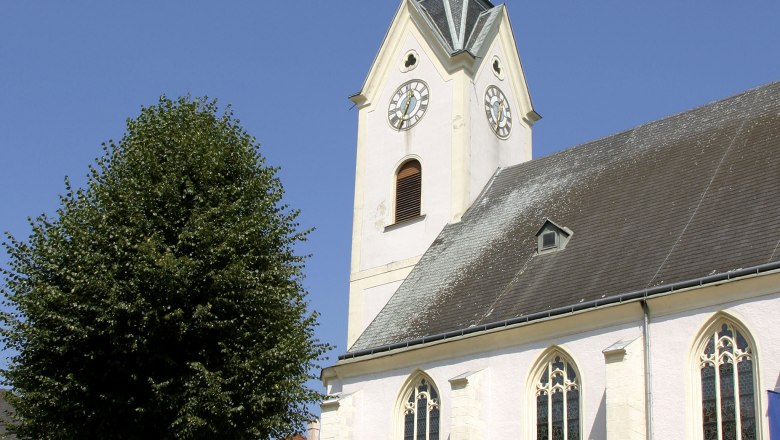 Stadtpfarrkirche St. Laurenz mit Turm und Uhr vor blauem Himmel.