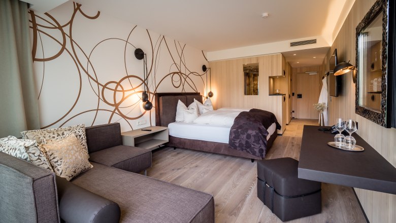 Modern eingerichtetes Hotelzimmer mit Doppelbett, Sofa und Schreibtisch.