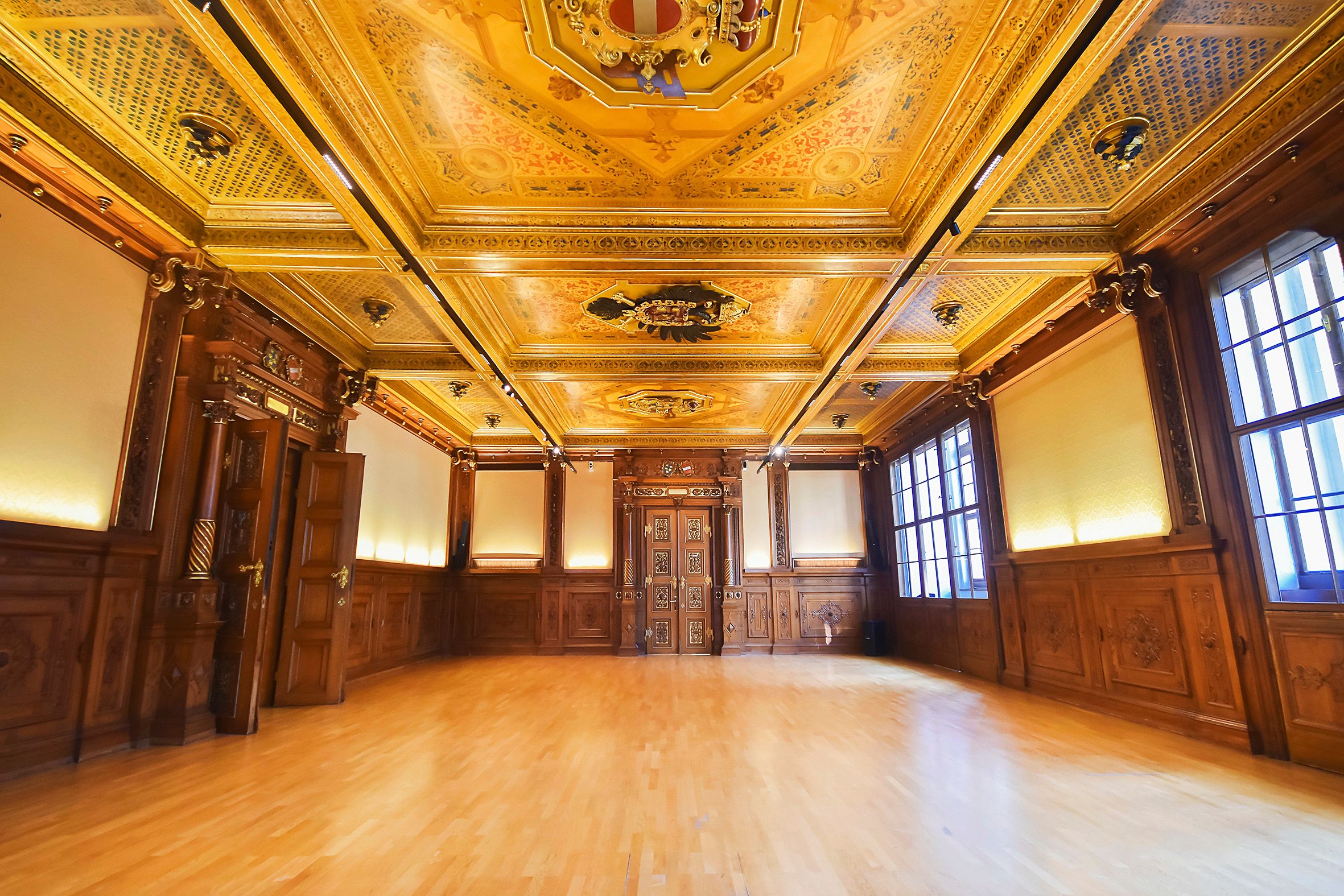 Prunkvoller Saal mit reich verzierter Holzdecke und Wänden im Palais Niederösterreich.
