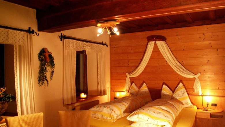 Gem&uuml;tliches Schlafzimmer mit Holzw&auml;nden und gelber Bettw&auml;sche.