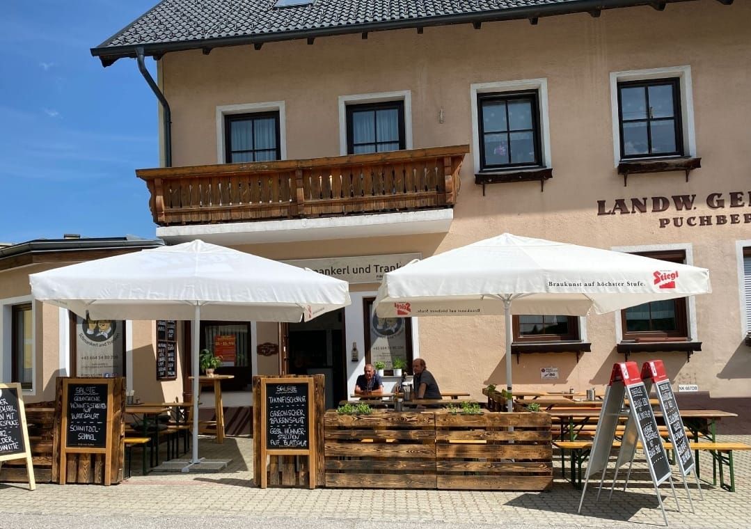 Außenbereich eines Restaurants mit Sonnenschirmen und Tafeln mit Speiseangeboten.