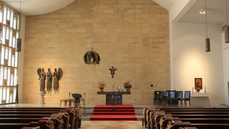 Innenansicht einer Kirche mit Altar, B&auml;nken und religi&ouml;sen Skulpturen.