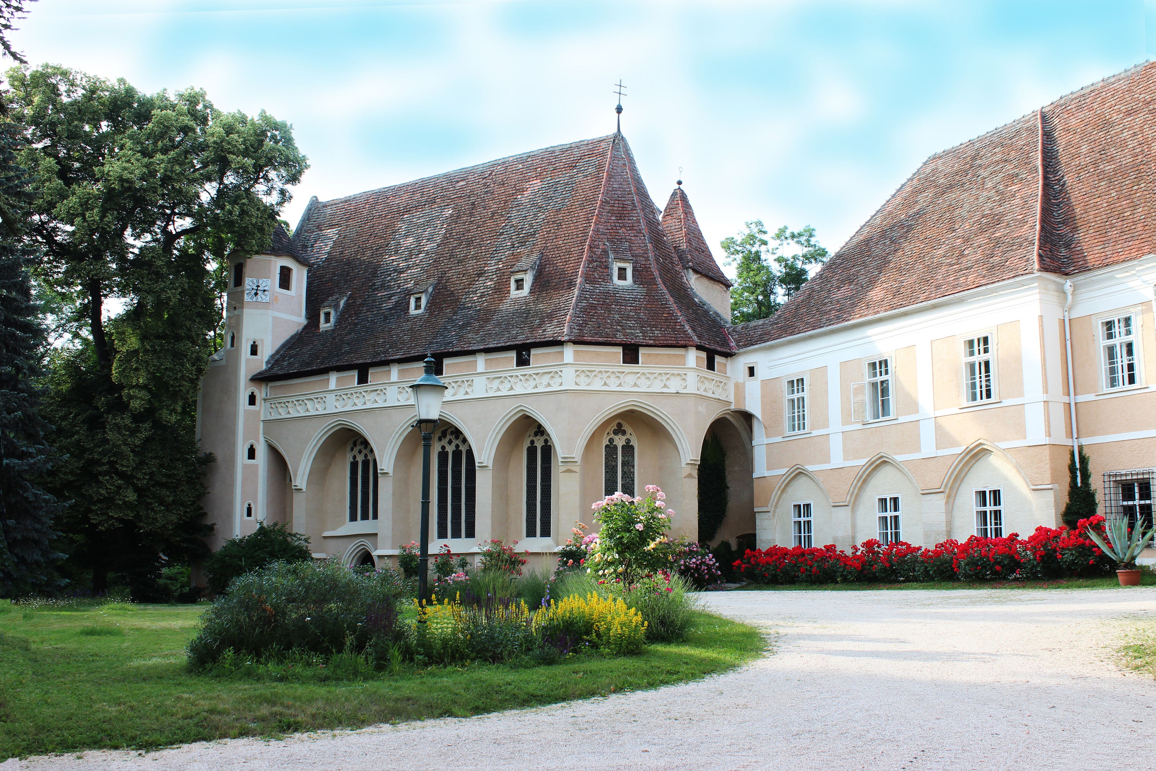 Historisches Gebäude mit Spitzdach und Garten im Vordergrund.