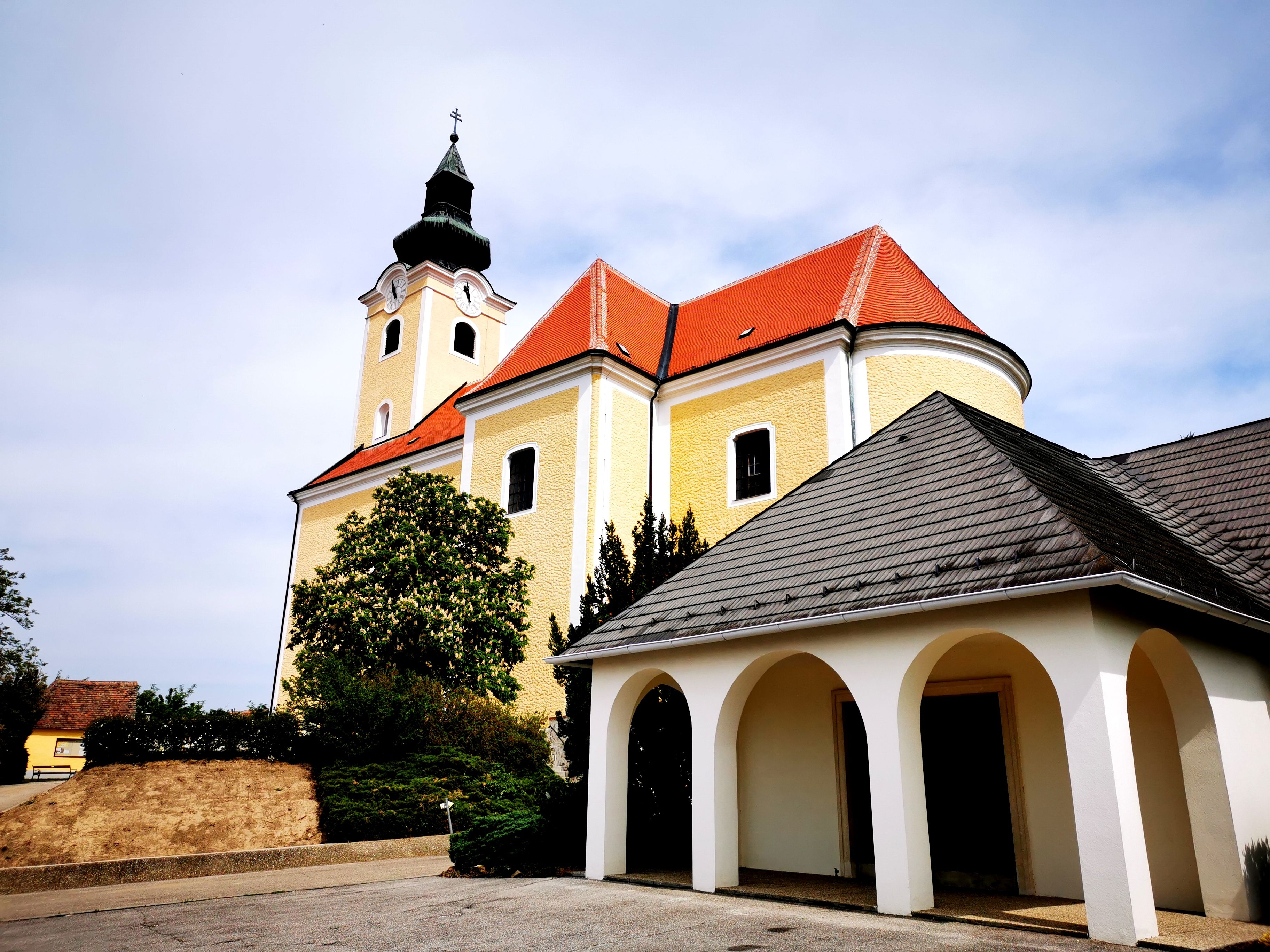Pfarrkirche St. Nikolaus in Röschitz mit gelber Fassade und rotem Dach.