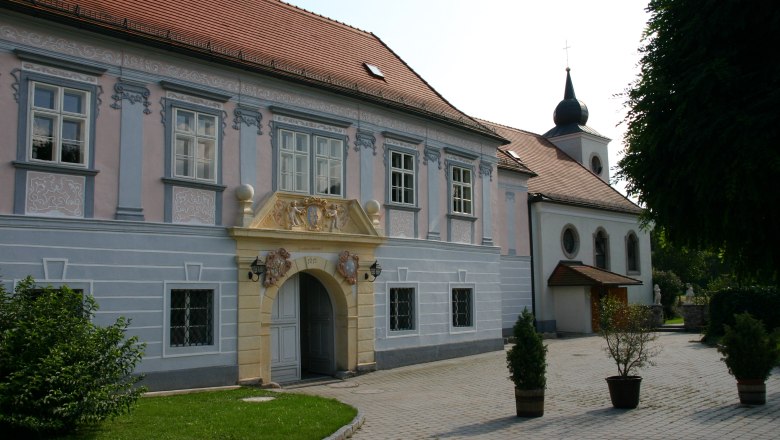Historisches Gebäude mit verziertem Eingang und Kirche im Hintergrund.