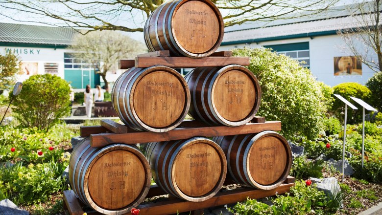 Holzf&auml;sser mit der Aufschrift 'Waldviertler Whisky J.H.' im Freien vor einem Geb&auml;ude.