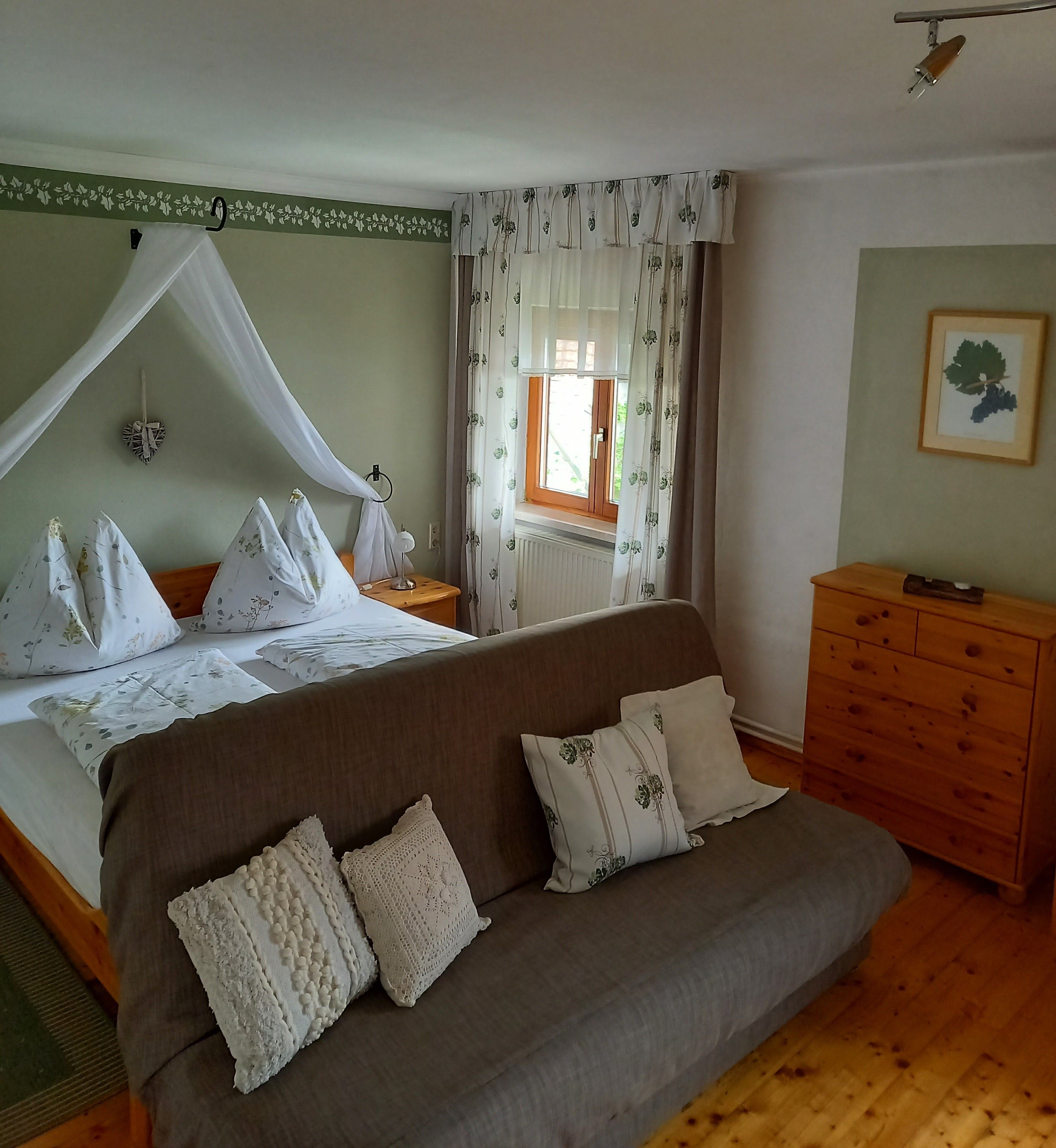 Gemütliches Gästezimmer mit Doppelbett, Sofa und Holzmöbeln.