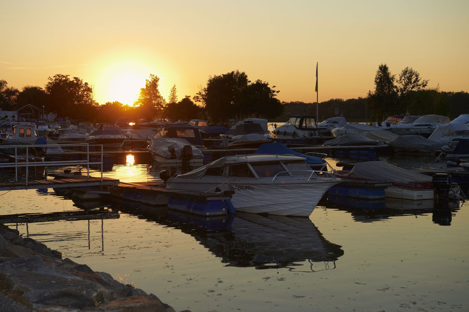 Sonnenuntergang über einem Yachthafen mit mehreren Booten im Wasser.