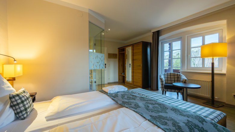 Hotel Schneeberghof, © Niederösterreich Werbung / Maximilian Pawlikowsky Hotelzimmer mit Doppelbett, Sessel, Tisch und Fenster mit Ausblick.