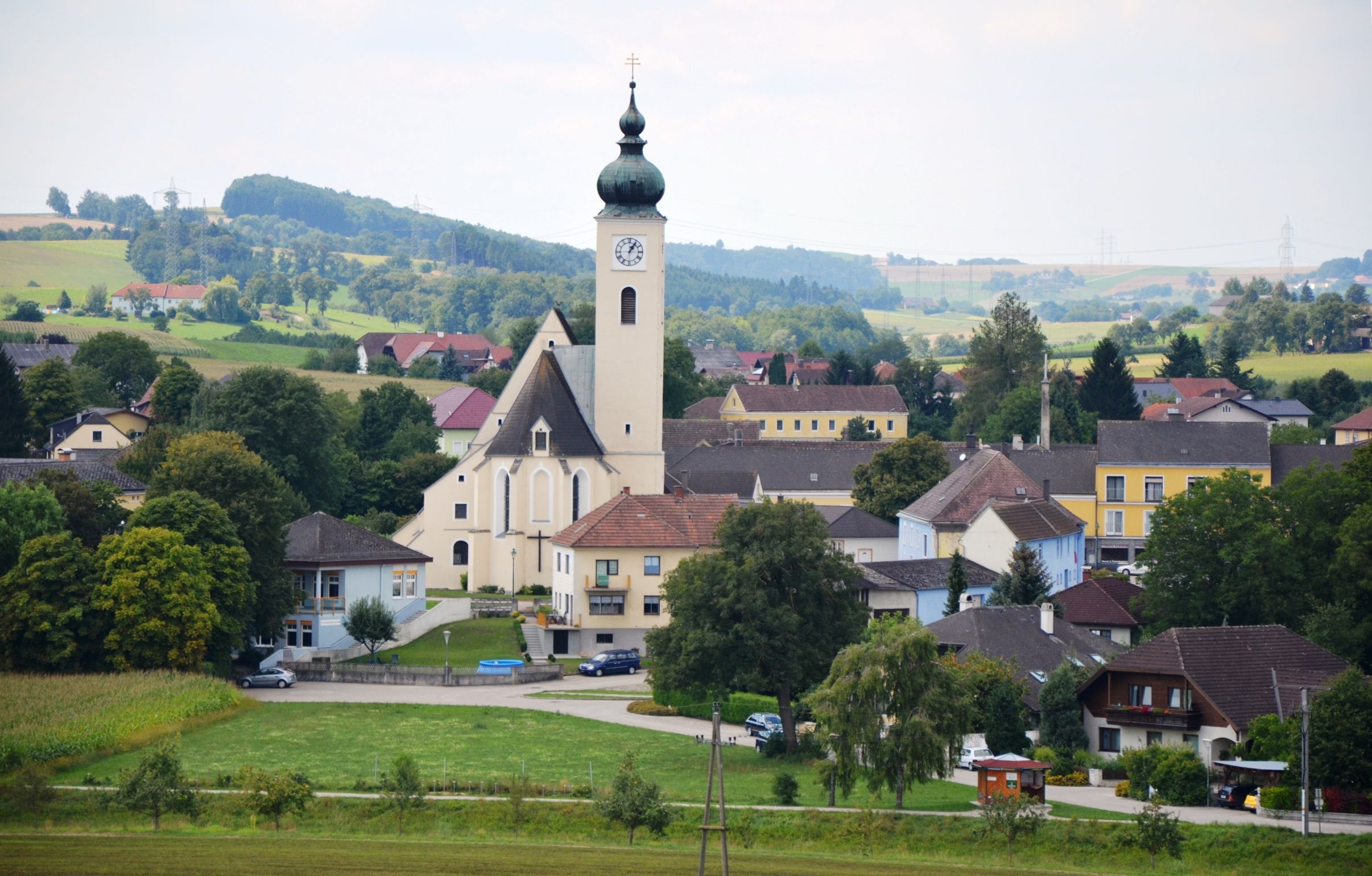 Blick auf die Marktgemeinde Ruprechtshofen mit Kirche und umliegenden Häusern in einer ländlichen Landschaft.