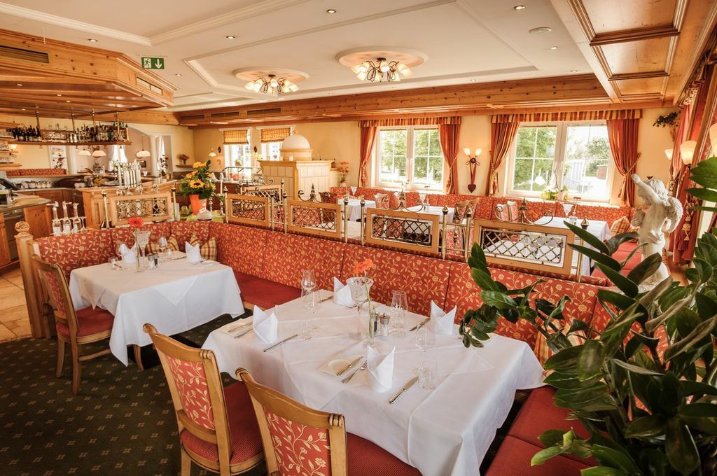 Elegantes Restaurant mit gedeckten Tischen und roten Polstermöbeln.