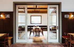 Gemütliches Restaurant mit Holzmöbeln und großen Fenstern.