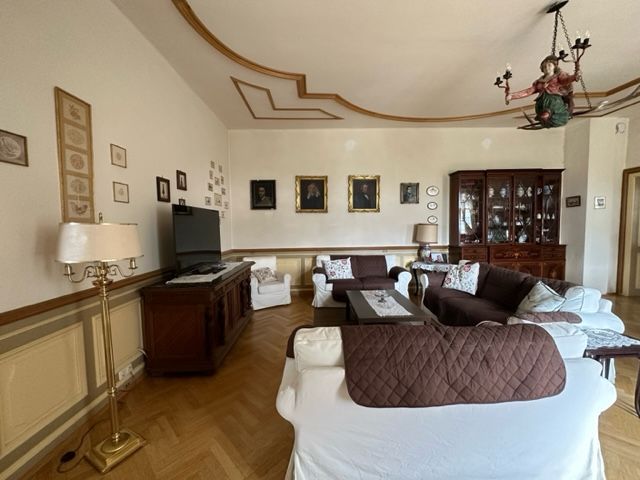 Elegantes Wohnzimmer mit antiken Möbeln, Gemälden an der Wand und einem Kronleuchter.