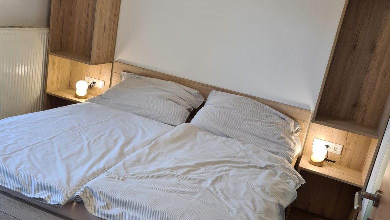Doppelzimmer mit Holzinterieur und Doppelbett, Nachttischlampen an beiden Seiten.