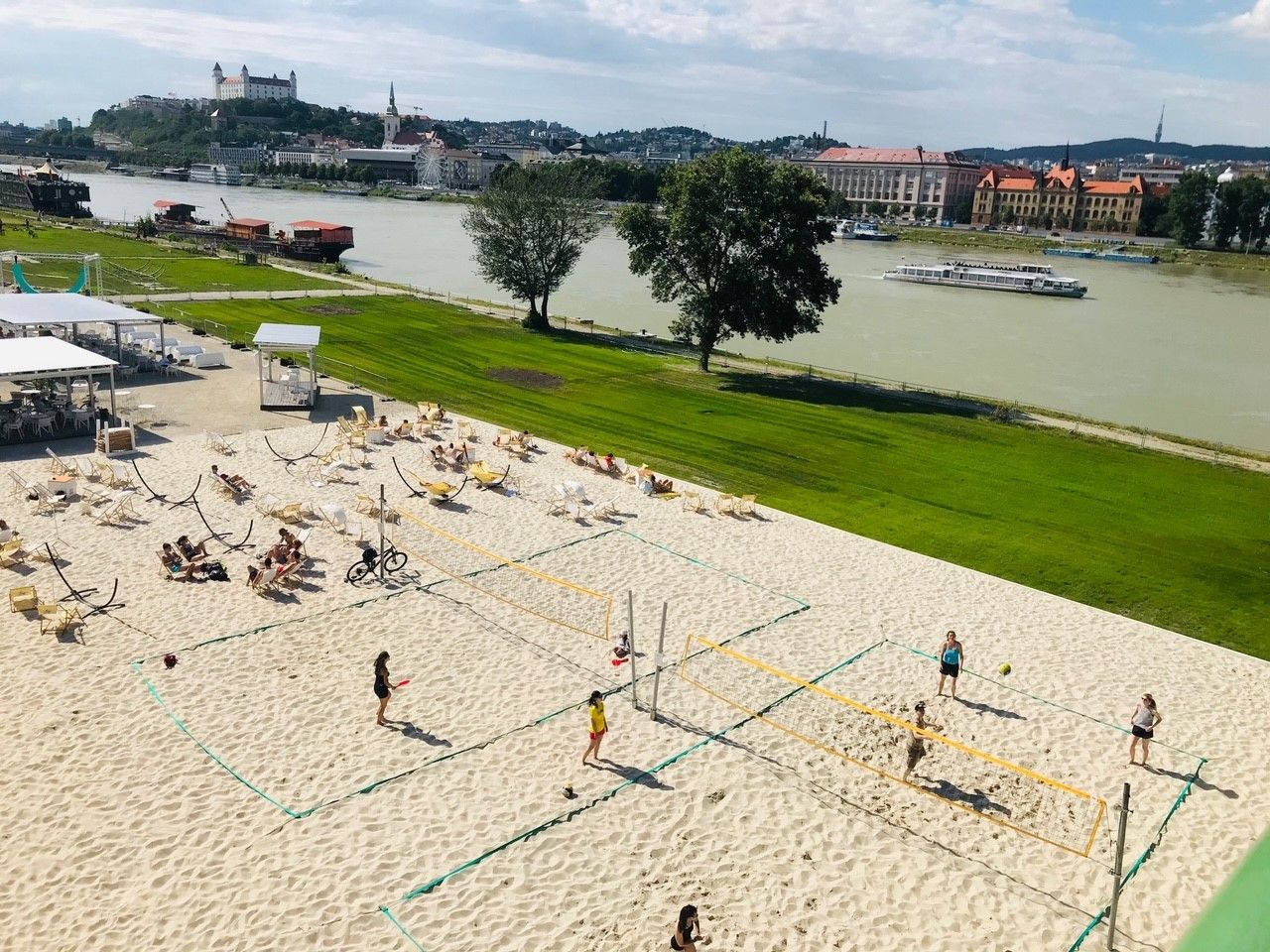 Donau bei Bratislava, Donauufer mit Sand, Liegestühlen und Menschen beim Ballspielen.