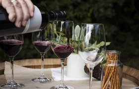 Hand gie&szlig;t Rotwein in Gl&auml;ser