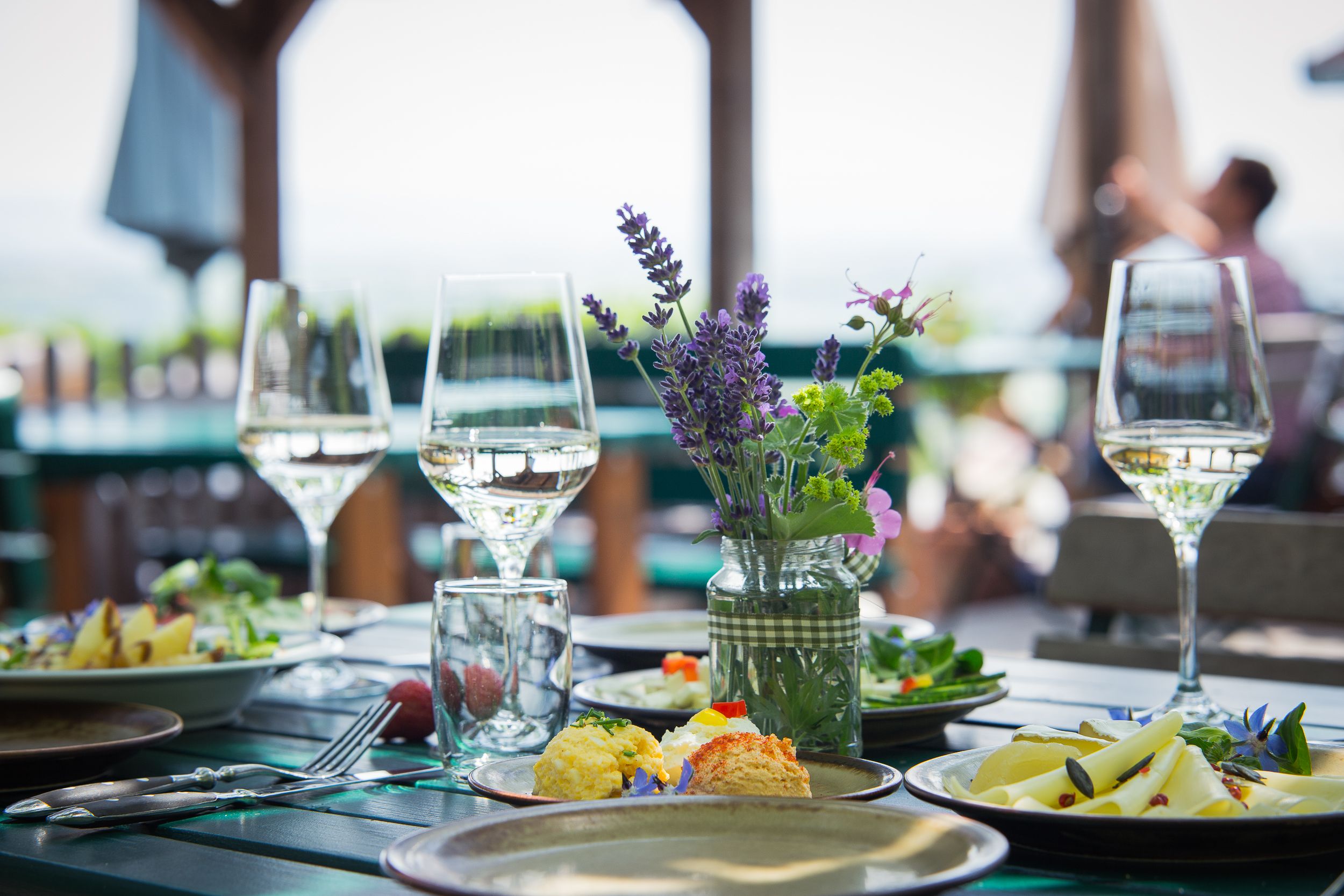 Ein gedeckter Tisch im Freien mit Weingläsern, Blumen und Speisen.