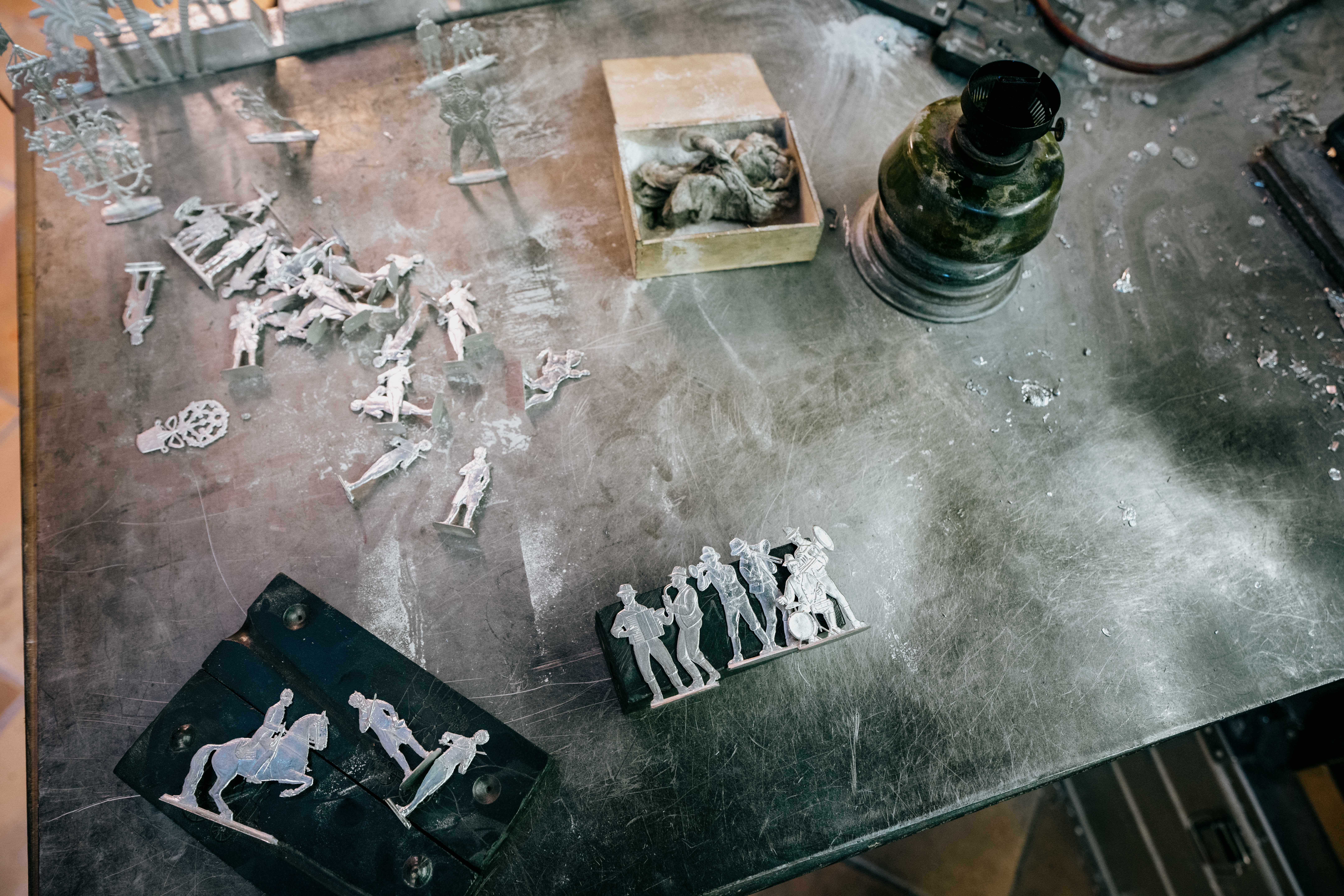 Unbemalte Zinnfiguren auf einem Tisch mit Werkzeugen und Materialien.