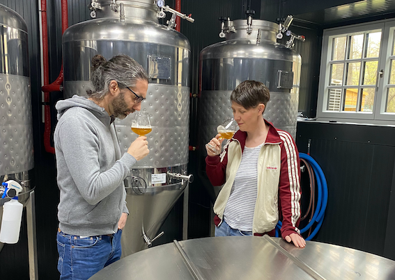 Innenansicht eines modernen Cafés mit Holzbalken, Bartresen und Tischen.