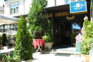 Eingang zu einem Restaurant mit Pflanzen und Schildern.