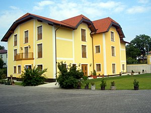 Gelbes zweist&ouml;ckiges Geb&auml;ude mit rotem Dach und gepflegtem Garten.