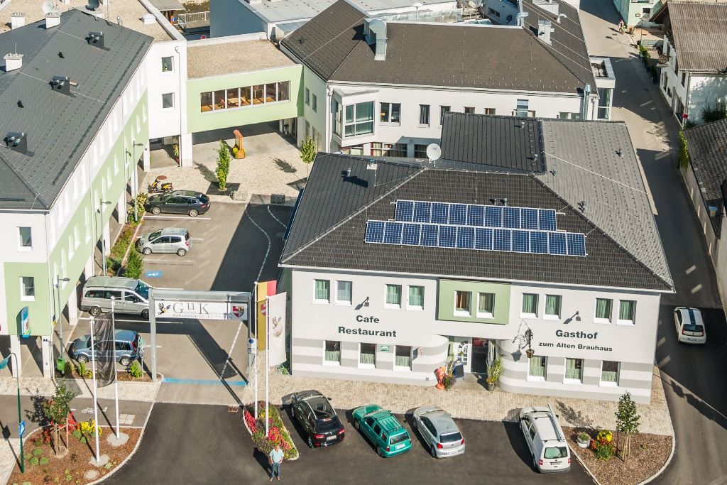Luftaufnahme eines Gebäudekomplexes mit dem Gasthof zum Alten Brauhaus, Solarpanels auf dem Dach und mehreren geparkten Autos.