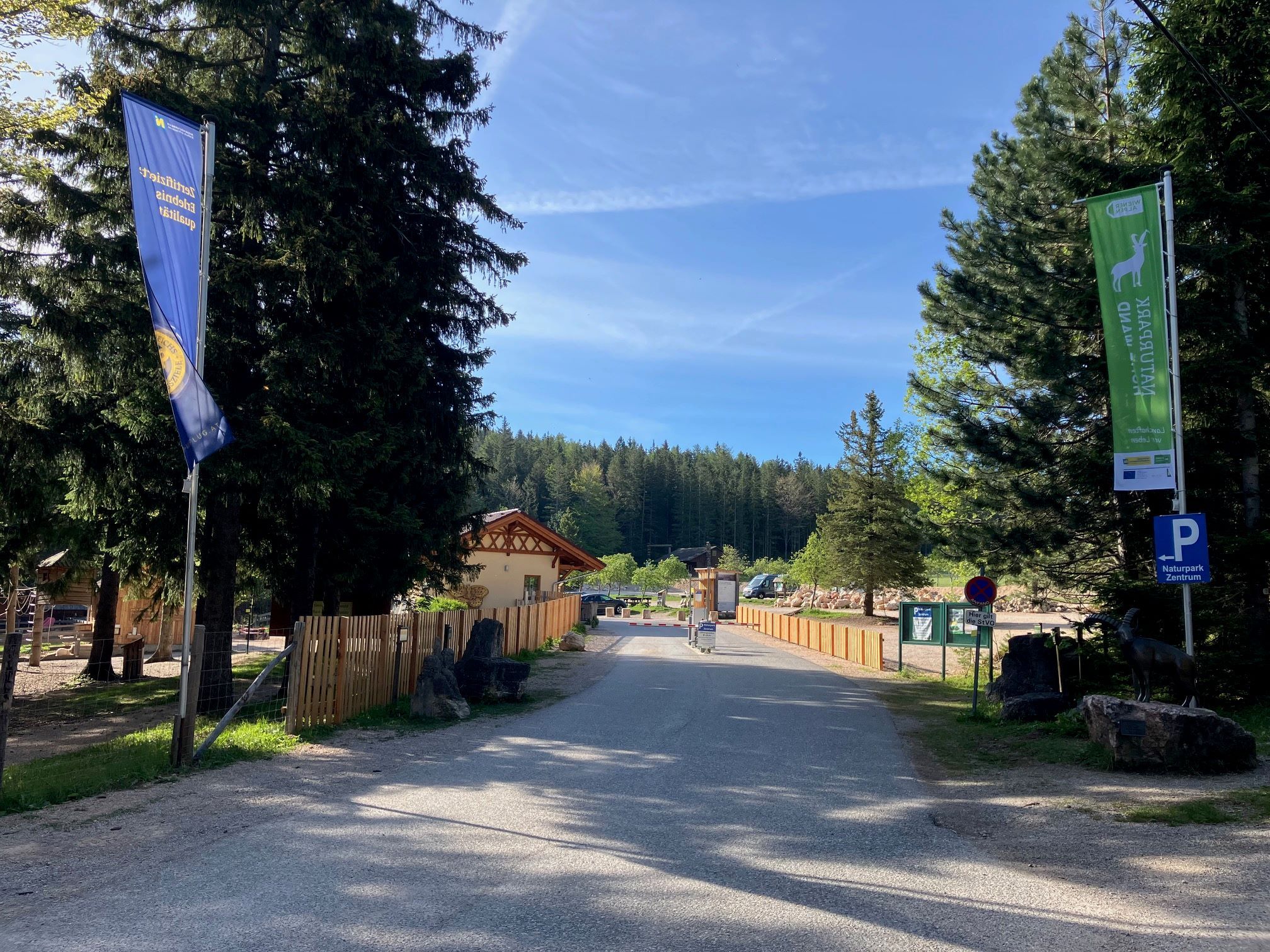 Einfahrt zum Naturpark Zentrum mit Fahnen und Bäumen.