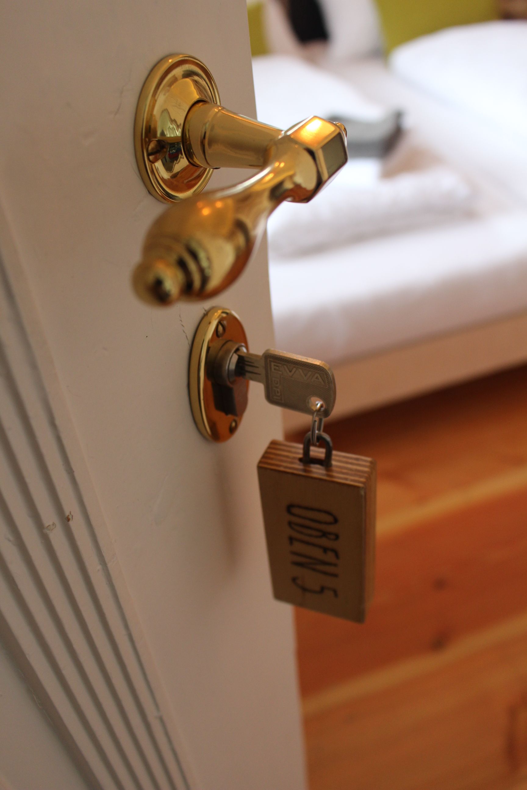 Nahaufnahme eines Türgriffs mit Schlüssel und Holzanhänger mit der Aufschrift 'OBEN 5'.