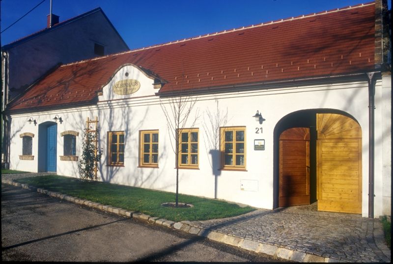 Weißes Gebäude mit rotem Dach und Holztüren, beschriftet mit 'Kleinhaus'.