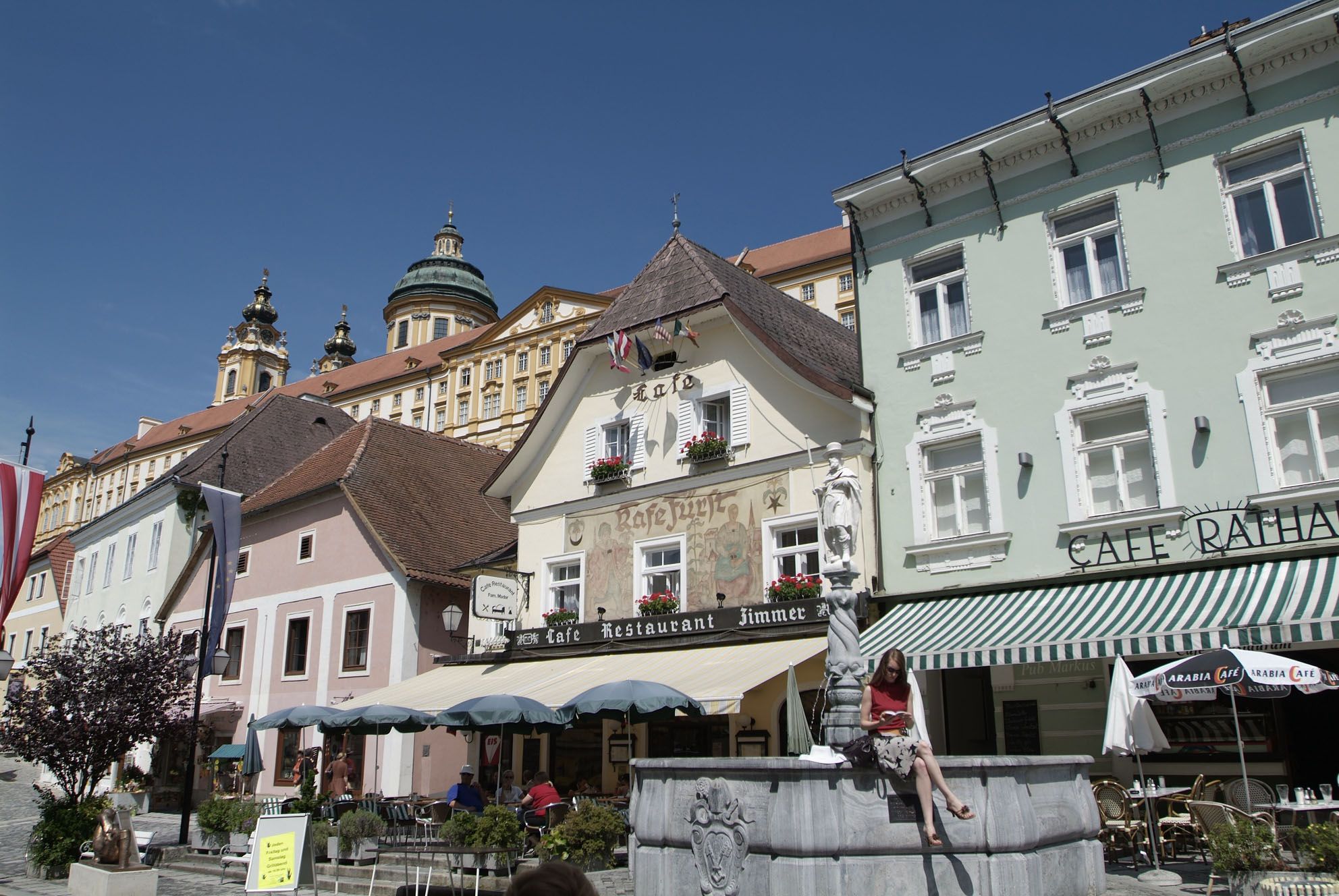 Straßenszene in der Altstadt von Melk mit historischen Gebäuden und einem Café.