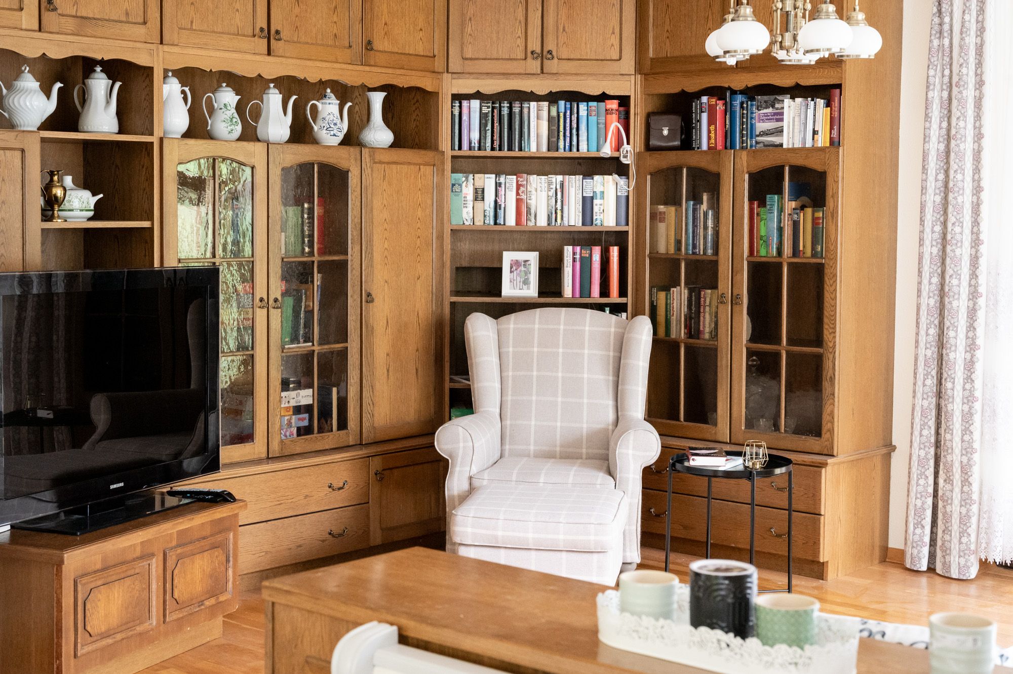 Wohnzimmer mit Bücherregal, Sessel und Fernseher.
