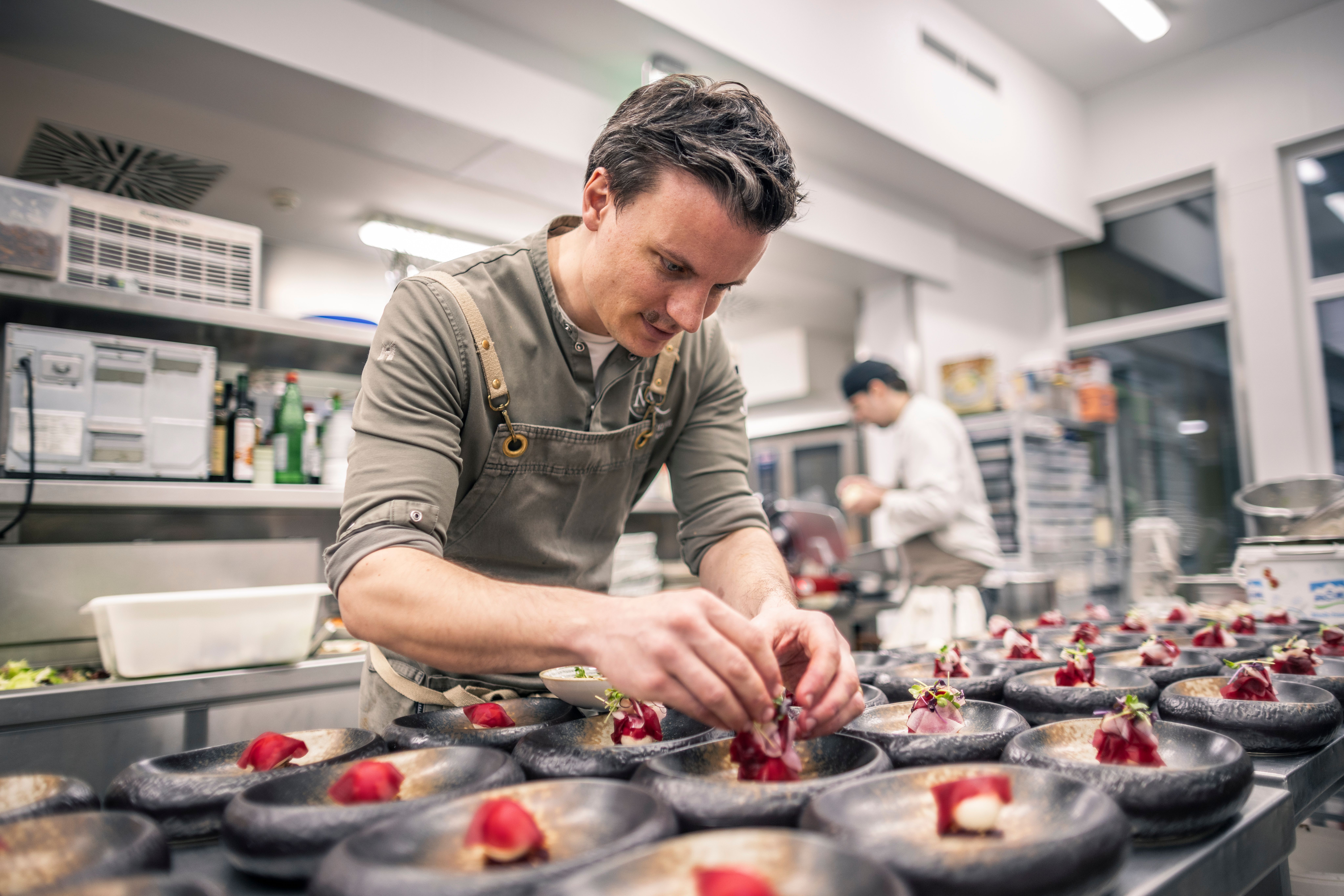 Hotelgebäude mit Naturteich und Liegestühlen im Vordergrund.