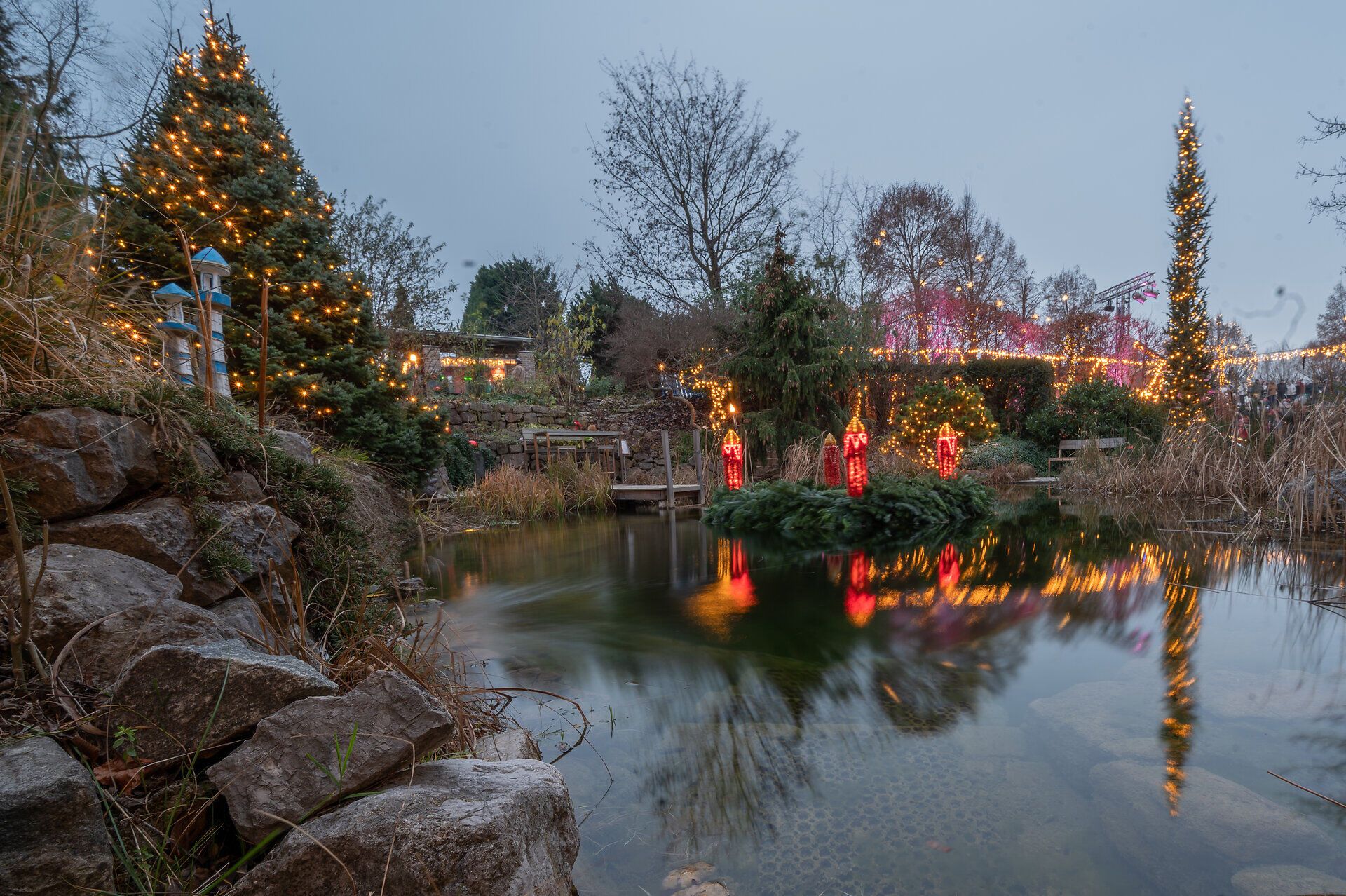In der besinnlichen Atmosphäre des Advents erstrahlen die Gärten in festlichem Glanz. Lichterketten funkeln an den Bäumen und spiegeln sich im ruhigen Wasser des Teiches, während der Duft von Glühwein und frisch gebackenem Gebäck die Luft erfüllt.
