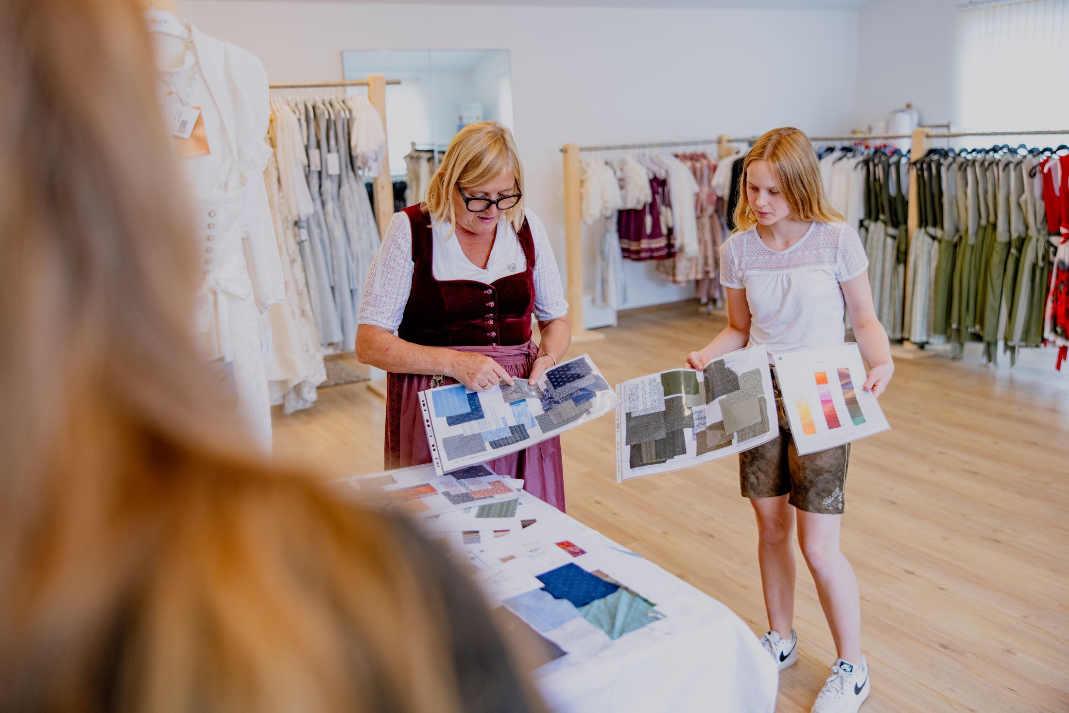 Zwei Frauen betrachten Stoffmuster in einem Trachtenmodegeschäft.