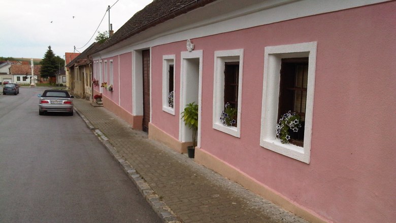 Stra&szlig;enansicht mit rosa Haus und parkendem Auto.