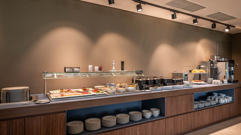 Ein Fr&uuml;hst&uuml;cksbuffet mit verschiedenen Speisen und Geschirr in einem modernen Raum.