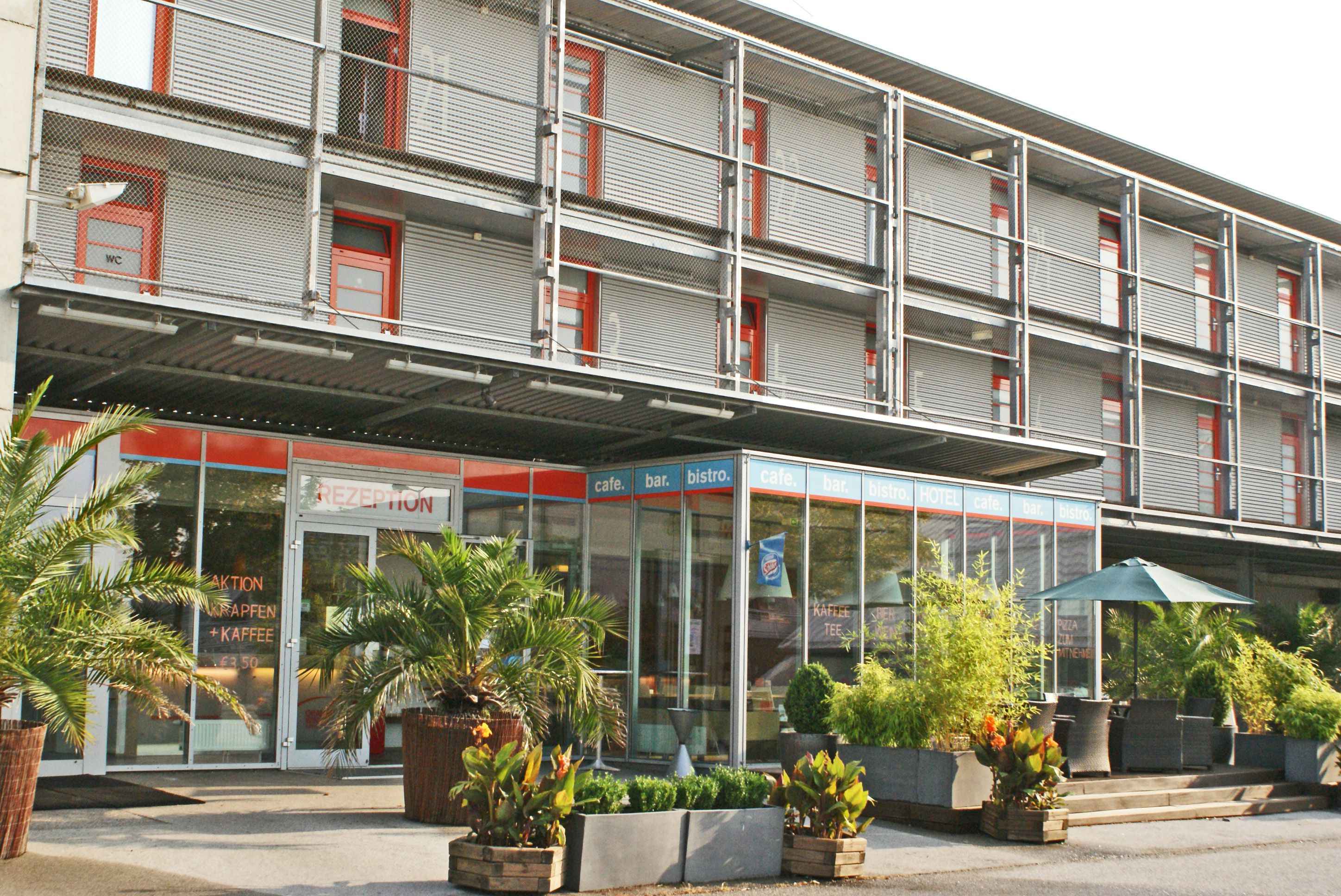 Moderne Hotel-Fassade mit Glasfront und Pflanzen.