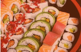 Eine Auswahl an Sushi-Rollen auf einem runden Tablett, dekoriert mit Wasabi und Ingwer.