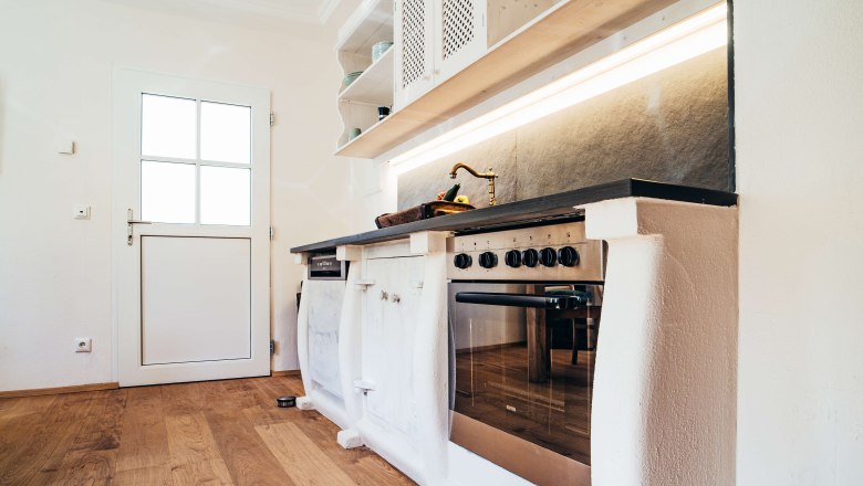 Moderne K&uuml;che mit Holzfu&szlig;boden, wei&szlig;er T&uuml;r und Edelstahlherd.