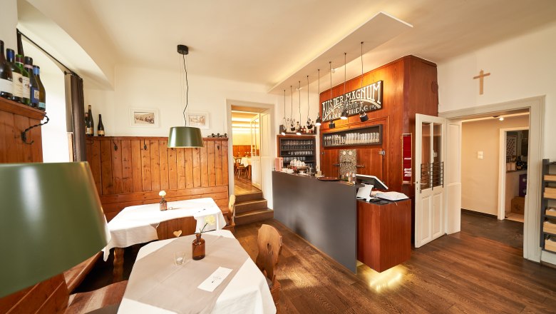 Innenansicht eines gem&uuml;tlichen Gastraums mit Holzm&ouml;beln und Theke.