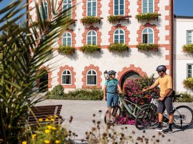 Die malerische Kulisse des Rathauses in Waidhofen l&auml;dt Radfahrer dazu ein, eine wohlverdiente Pause einzulegen. Bunte Blumenbeete umrahmen den Platz und schaffen eine einladende Atmosph&auml;re, die den Sommer in den Bergen perfekt widerspiegelt.
