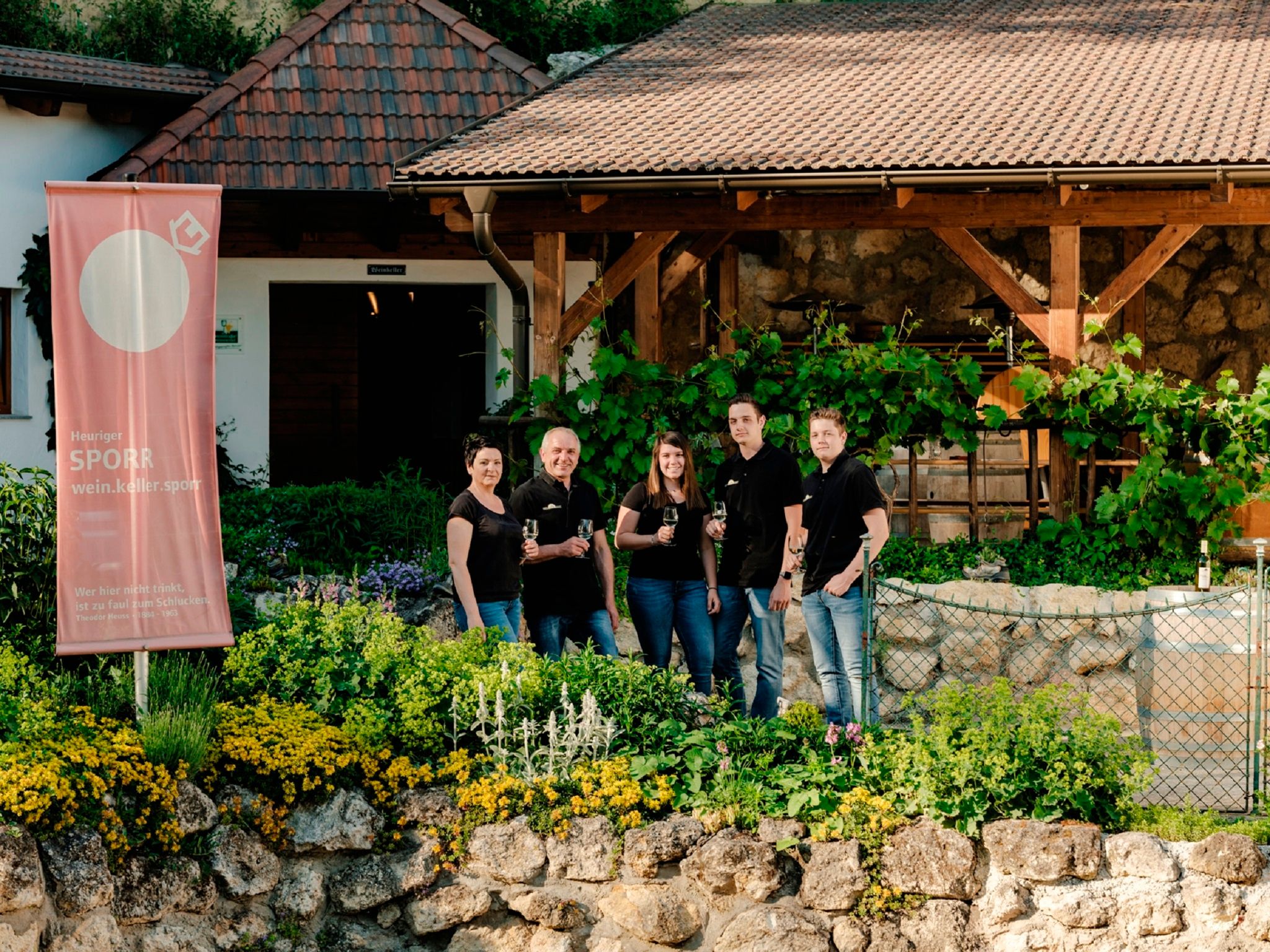 Gruppe von fünf Personen vor einem Weingut mit Sporr-Banner.