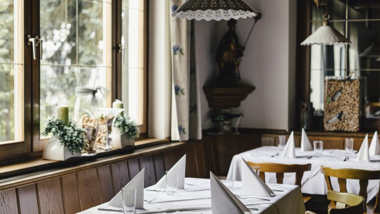 Innenansicht eines gem&uuml;tlichen Restaurants mit gedeckten Tischen und Holzst&uuml;hlen.