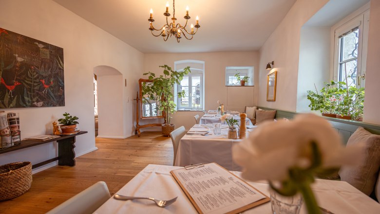 Gem&uuml;tliches Restaurant mit Holzboden, wei&szlig;en Tischdecken und Pflanzen.