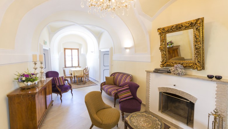 Eleganter Raum mit Kamin, antiken Möbeln und Kronleuchter.