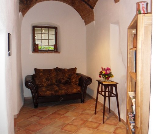 Historischer Raum mit Terrakota-Fliesen und einer zweisitzrigen Couch in dunkelbaun