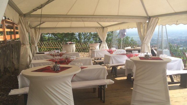 Festzelt mit gedeckten Tischen und Stehtischen, dekoriert für eine Feier.